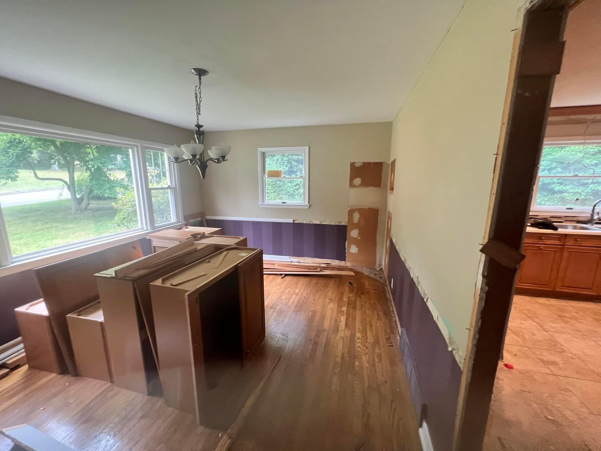 Kitchen renovation in progress with cabinet installation and beautiful hardwood floors