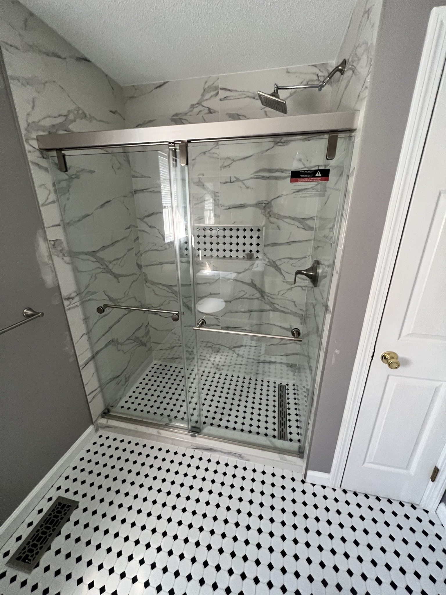 Modern shower with marble-look tile and glass sliding door
