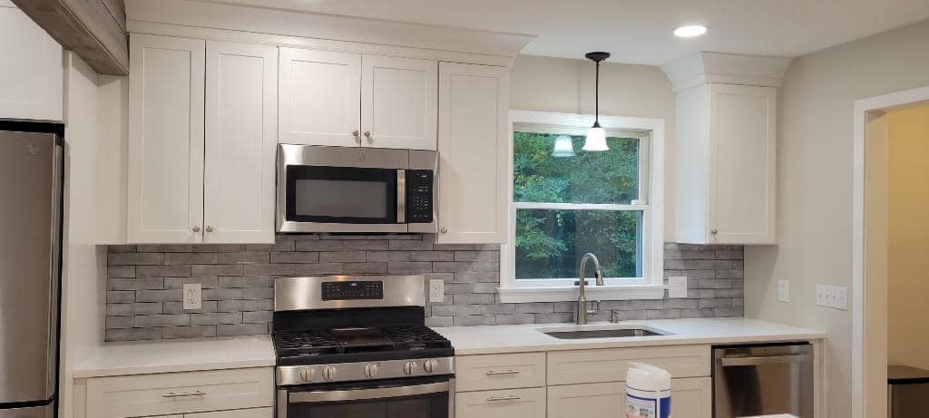 Elegant kitchen featuring white cabinetry, subway tile backsplash, and pendant lighting