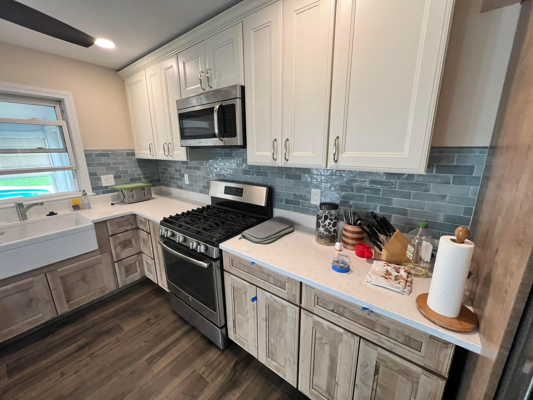 Contemporary kitchen with dark lower cabinets, white uppers, and marble countertops