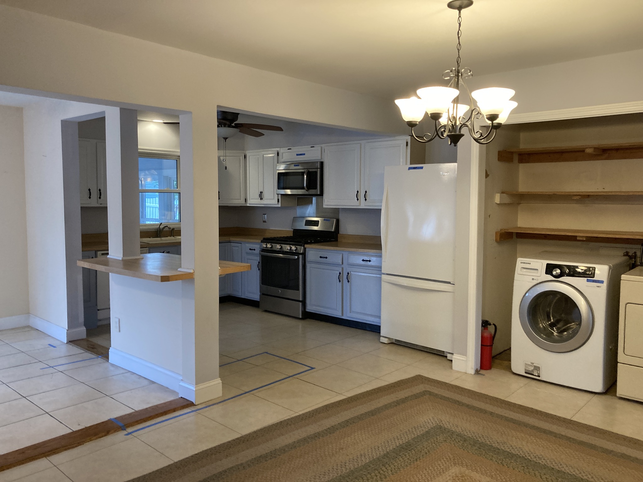 Open concept kitchen with white cabinets, breakfast bar, and adjacent laundry area