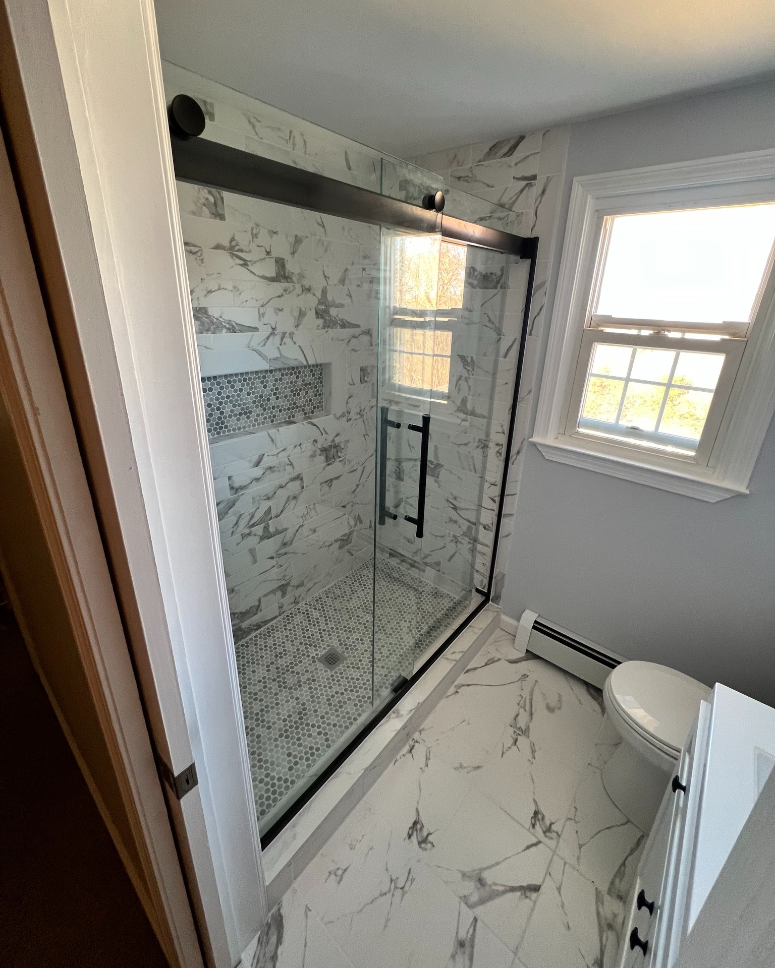 Beautiful marble shower design with black fixtures and glass door