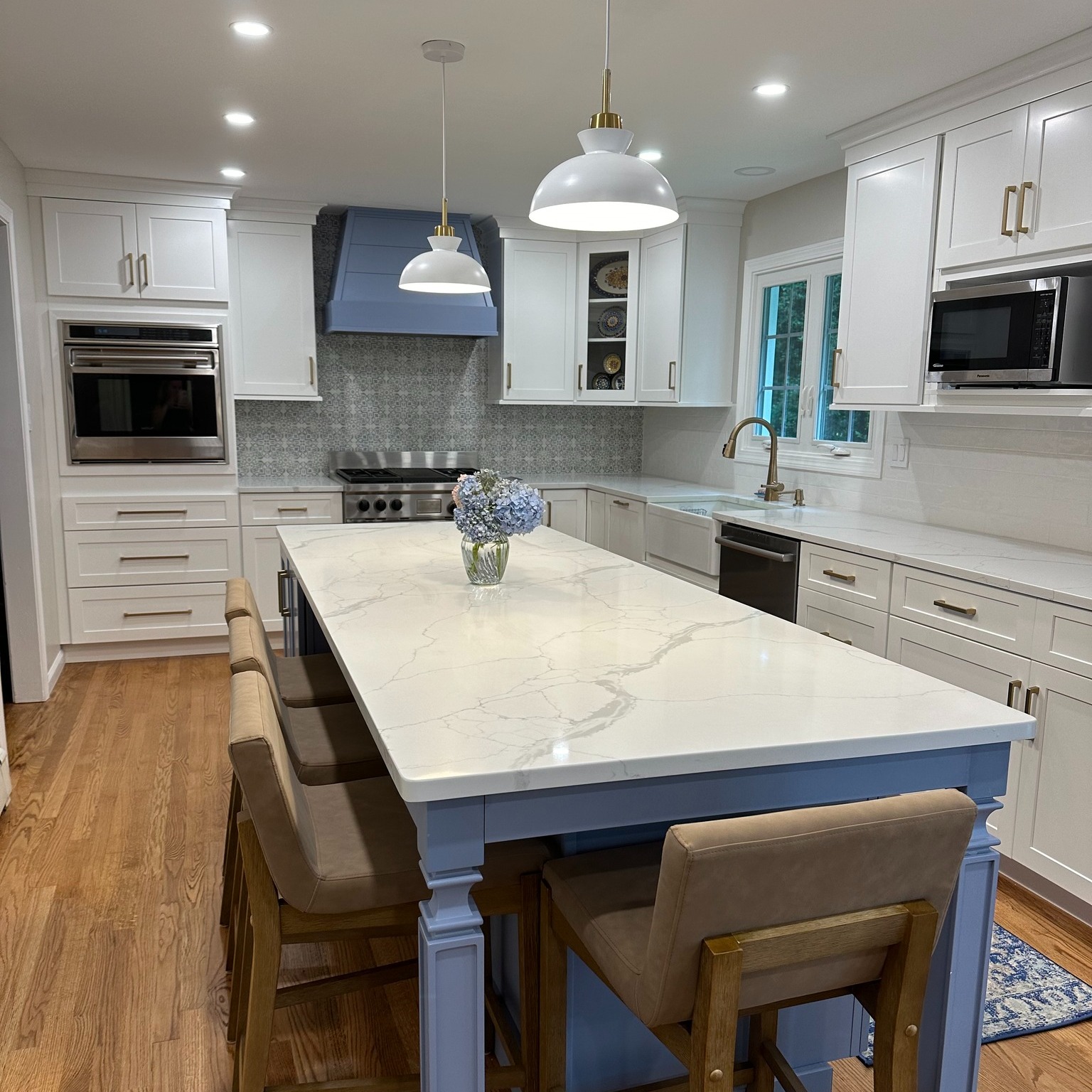Custom kitchen featuring white upper cabinets, blue island, and professional appliances