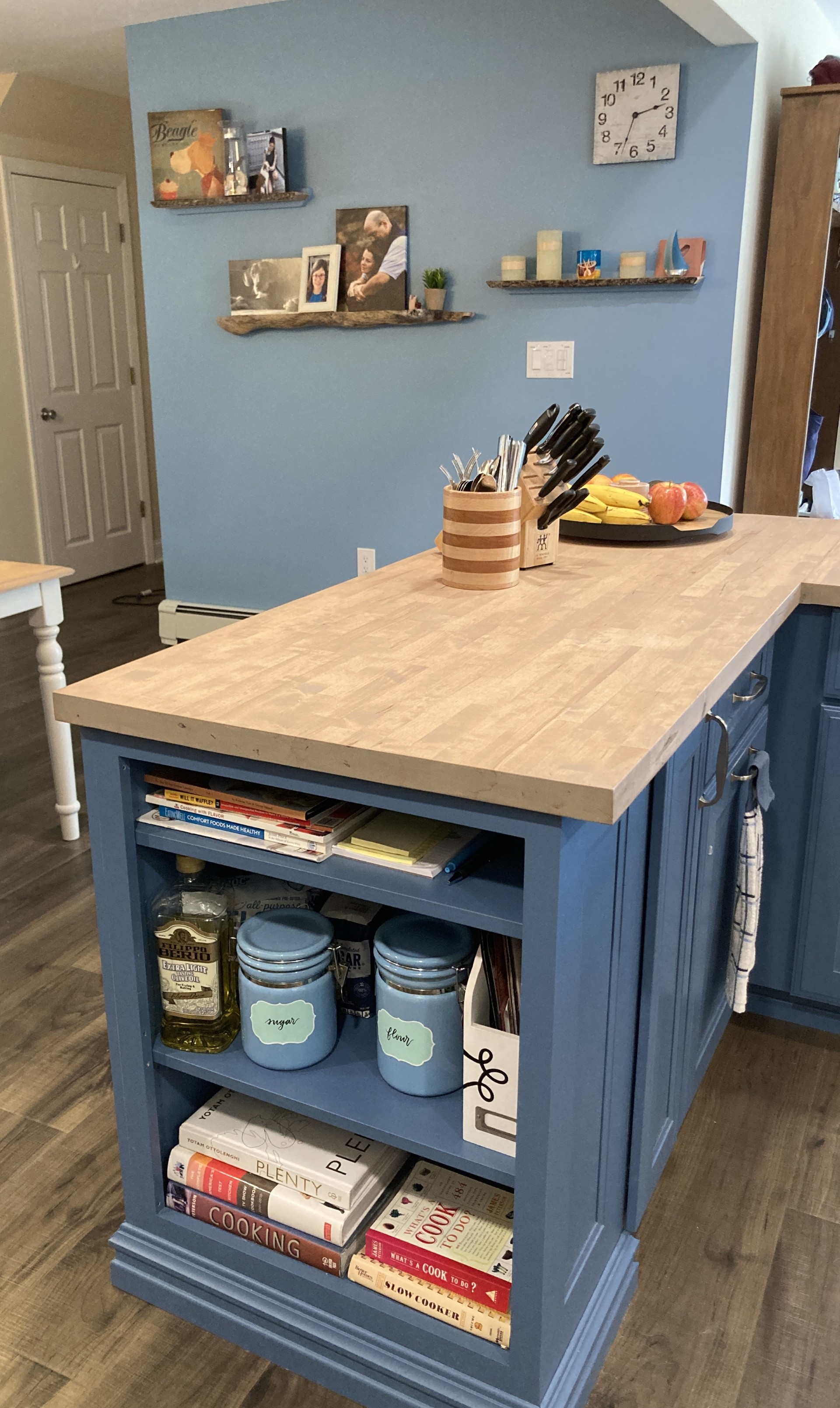 Contemporary kitchen with blue island, open shelving, and butcher block countertops