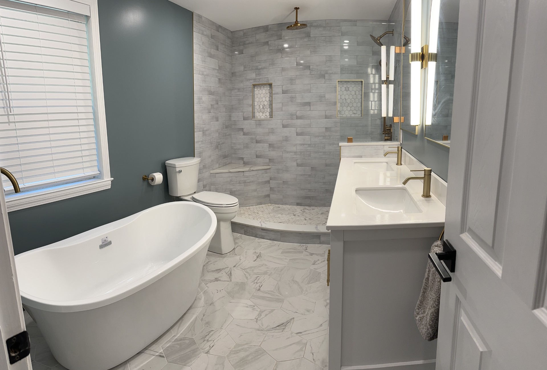 Modern bathroom featuring freestanding tub, teal accent wall, and marble tile shower
